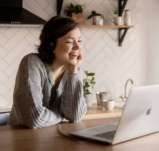 A woman happily engaged in video call on her laptop
